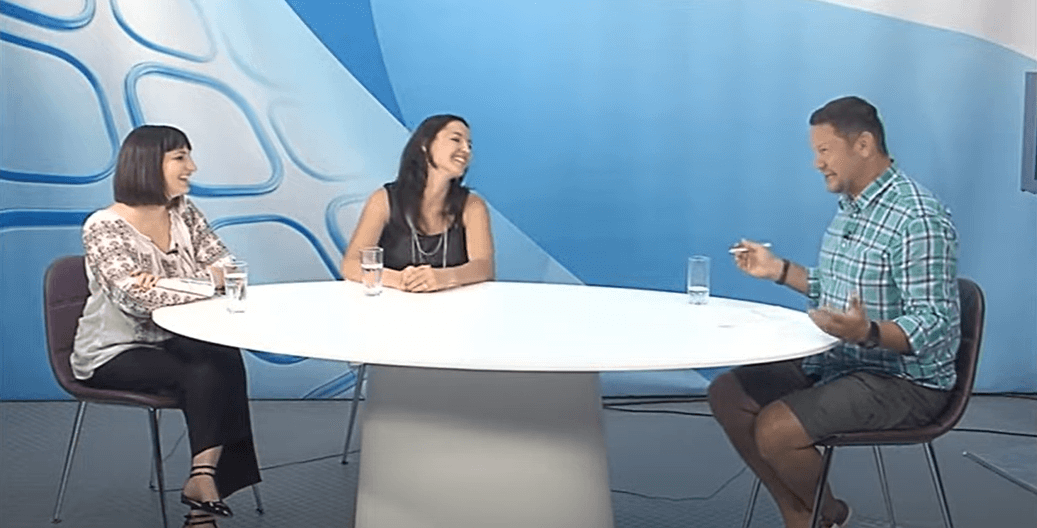 Trei persoane discută la o masă rotundă în studio.