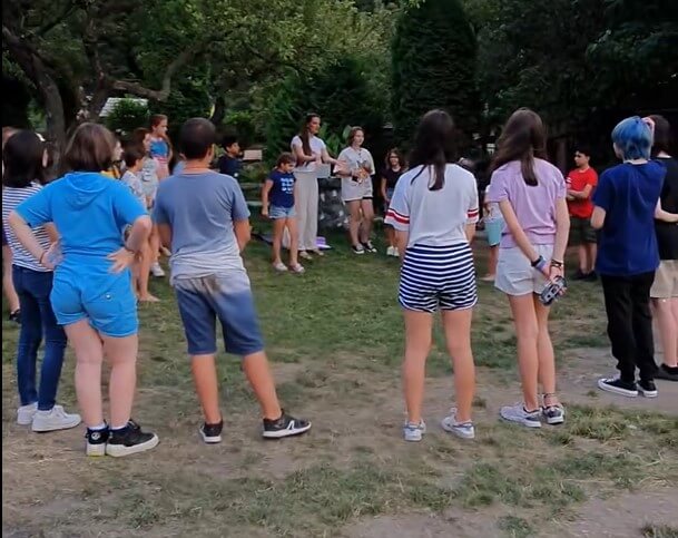 Copii stând într-un cerc în aer liber.