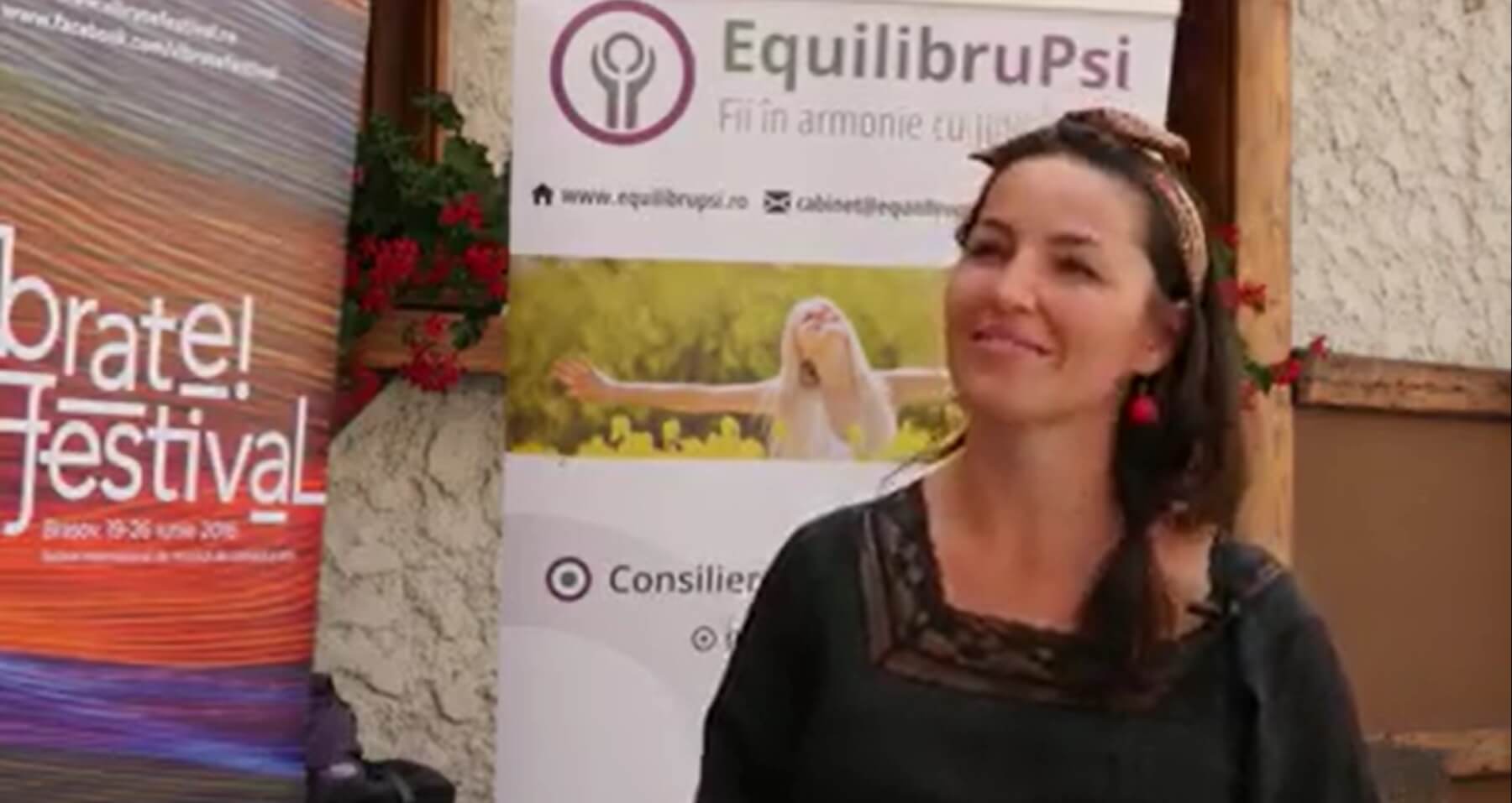 Femeie lângă afiș al unui festival.